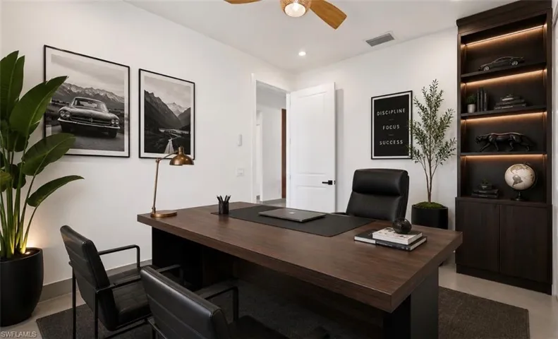 Dedicated workspace featuring a wood-finish desk, recessed lighting, and a ceiling fan