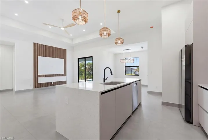 Contemporary kitchen island featuring a light-toned countertop, integrated sink with a black faucet, and a built-in dishwasher