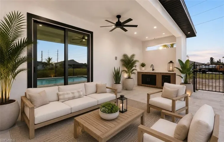 Expansive covered patio featuring a built-in outdoor kitchen with sink, matte black fixtures, and integrated cabinetry