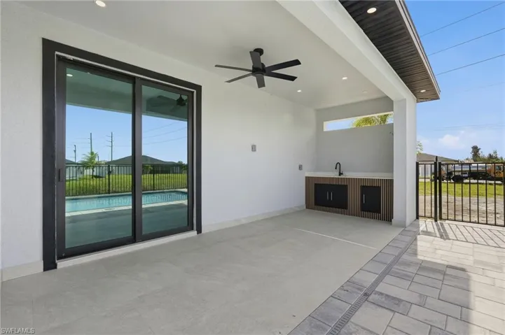 Covered patio featuring an outdoor kitchen with built-in cabinetry, sink, and countertop