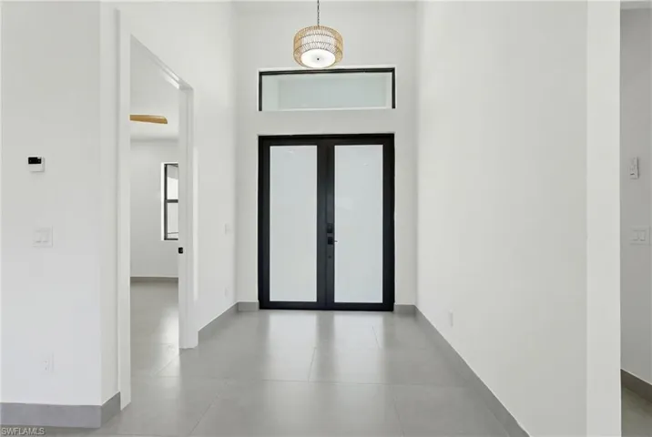 Entryway featuring double doors with frosted glass panels, a transom window, and a woven pendant light fixture