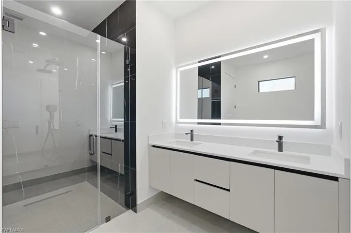 Modern bathroom featuring a frameless glass shower enclosure with a rain shower head and handheld sprayer