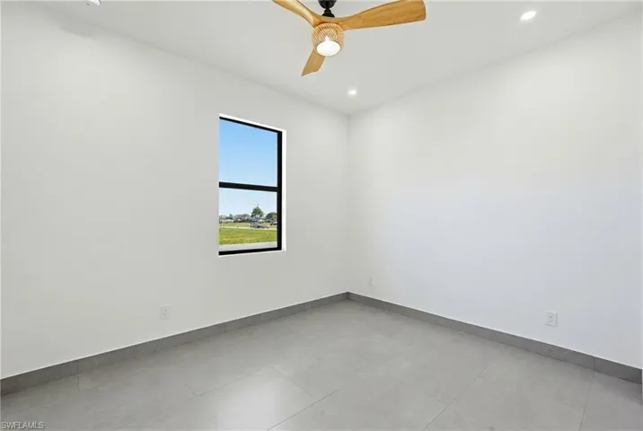 Bright interior space featuring a window with black trim, recessed lighting, and a wood-finish ceiling fan with a wicker-style light fixture