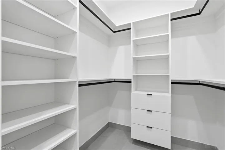 Custom white shelving system featuring integrated drawers and hanging rods
