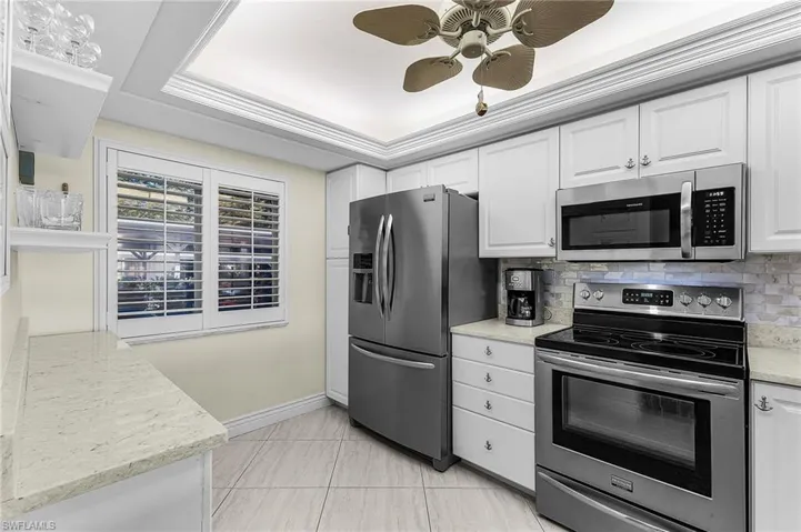 White cabinets, stainless steel appliances, tile backsplash, designer ceiling w/accent lighting, and floating shelves over the custom built in floating cabinets makes preparing meals in this kitchen a dream.