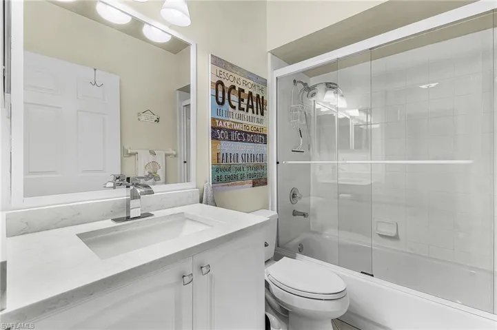 The guest bathroom is beautifully updated with higher vanity, glass shower doors, light, and fixtures.