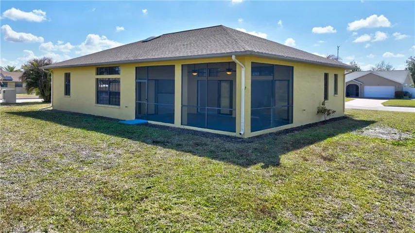Back of property with stucco siding, a lawn, and a sunroom