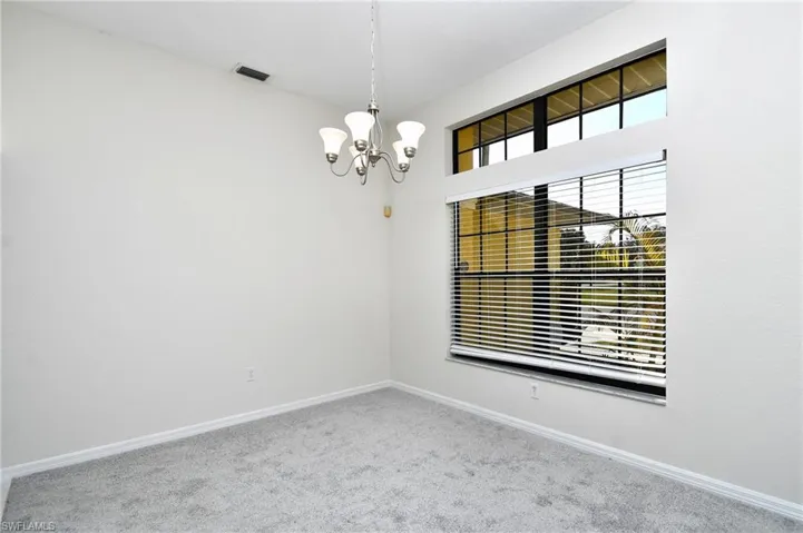 Spare room featuring light carpet and suspended lighting