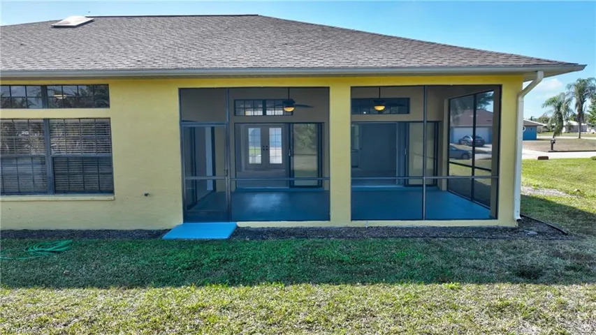 Back of property featuring a sunroom, a yard, stucco siding, and roof with shingles