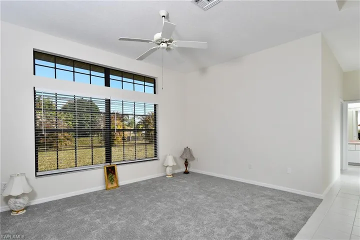 Tiled spare room featuring carpet floors and a ceiling fan