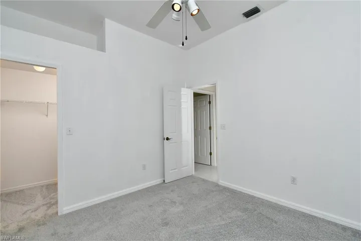 Unfurnished bedroom with carpet floors, a walk in closet, and a ceiling fan
