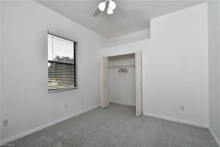 Unfurnished bedroom featuring light carpet, ceiling fan, and a closet