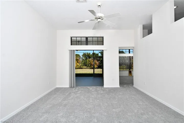 Carpeted spare room featuring ceiling fan and a high ceiling