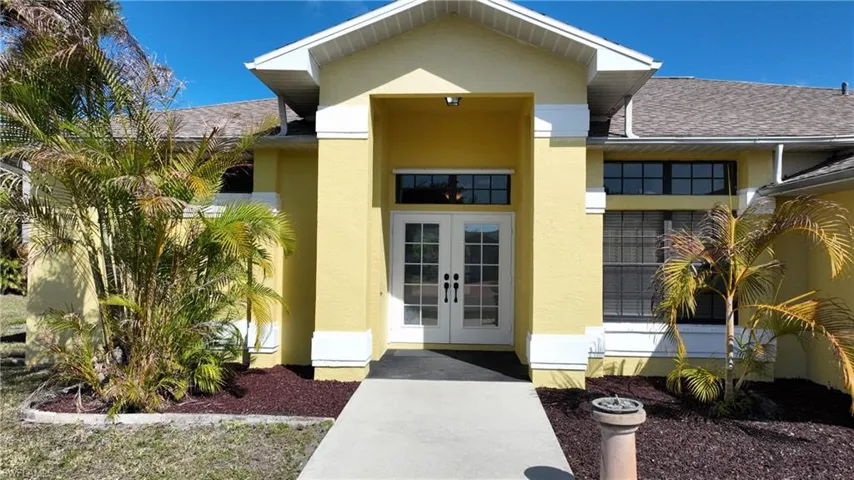View of exterior entry with french doors, stucco siding, and a shingled roof