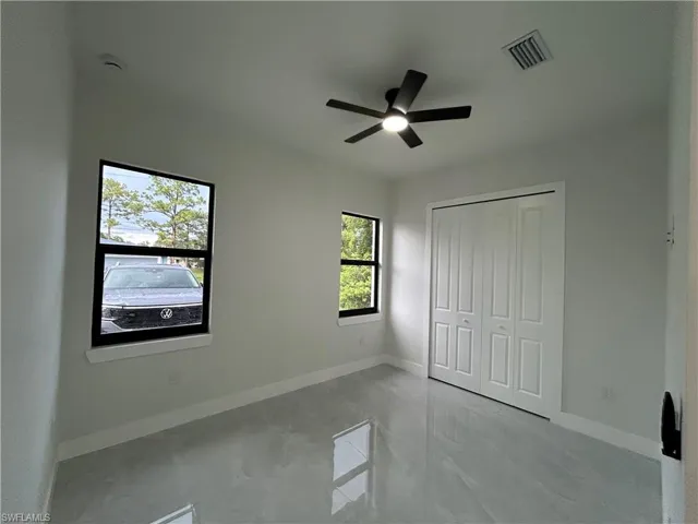 Unfurnished bedroom with a closet, a ceiling fan, and marble finish flooring