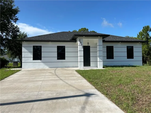 View of front facade with roof with shingles and a front lawn