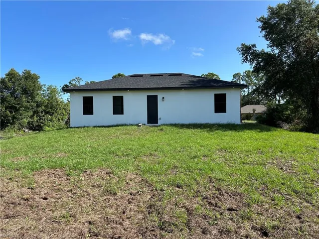 Rear view of house with stucco siding and a lawn