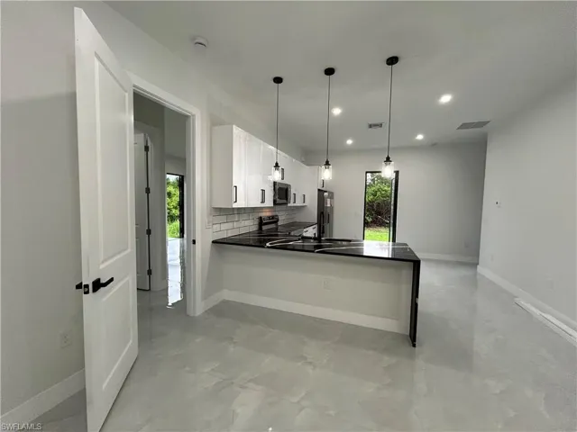 Kitchen with plenty of natural light, finished concrete floors, a peninsula, white cabinets, and recessed lighting