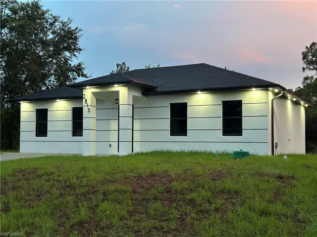 View of home's exterior featuring stucco siding, a shingled roof, and a lawn