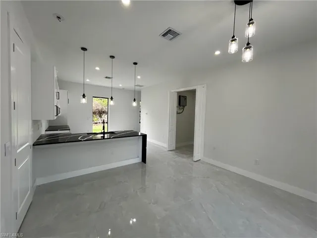 Kitchen featuring white cabinets, dark countertops, recessed lighting, baseboards, and a peninsula