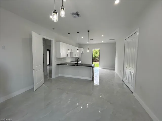Kitchen featuring dark countertops, open floor plan, white cabinetry, baseboards, and recessed lighting