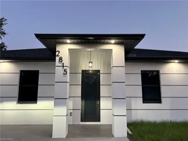 View of exterior entry featuring a shingled roof