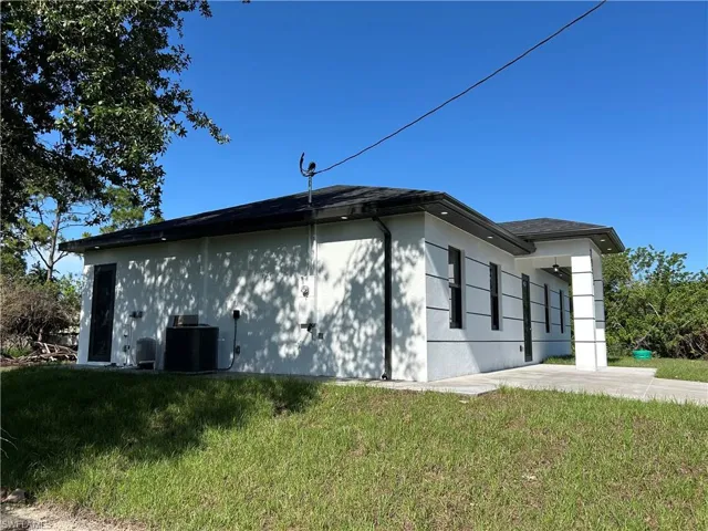 View of home's exterior featuring cooling unit, a lawn, and stucco siding
