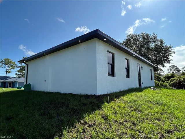 View of property exterior with stucco siding and a lawn