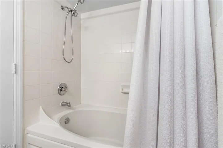 Bathtub and shower combination with white tile surround and chrome fixtures