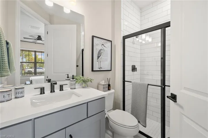 Bathroom with vanity, toilet, a shower stall, visible vents, and a ceiling fan