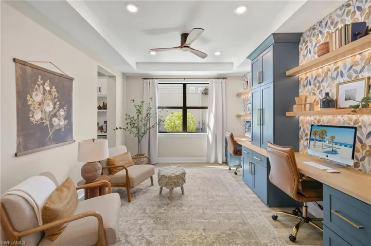 Office with a ceiling fan, a raised ceiling, built in desk, light wood-style floors, and recessed lighting