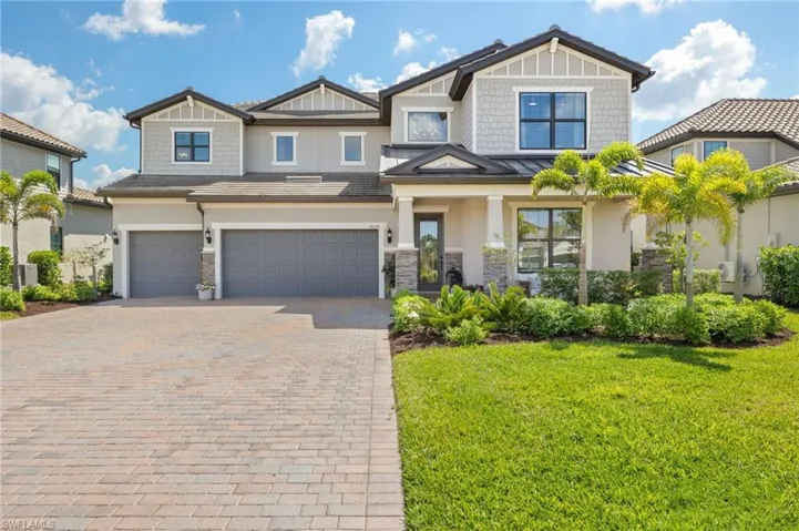 View of front of property featuring stone siding, stucco siding, an attached garage, a front lawn, and decorative driveway