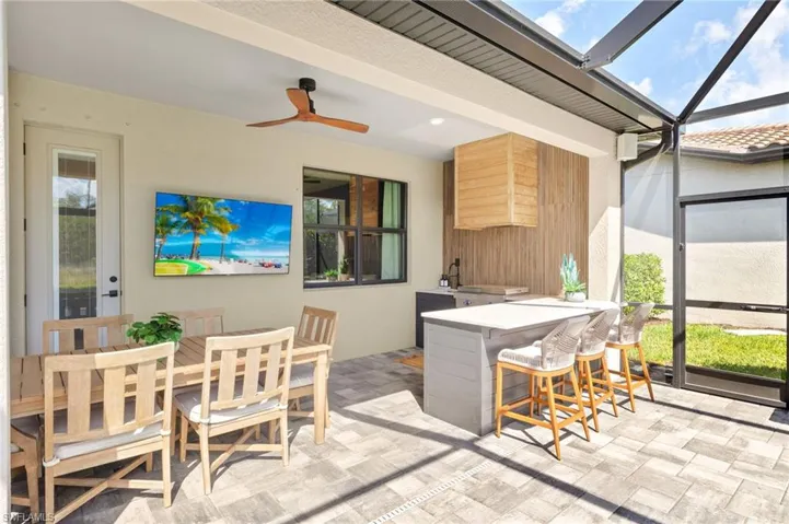 View of patio / terrace featuring a lanai, ceiling fan, outdoor dining space, and outdoor dry bar