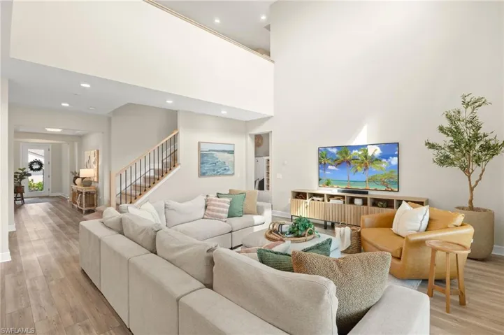 Living area featuring baseboards, recessed lighting, stairway, and light wood-type flooring