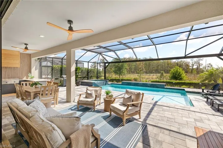 View of pool with glass enclosure, an outdoor living space, a pool with connected hot tub, a patio area, and ceiling fan