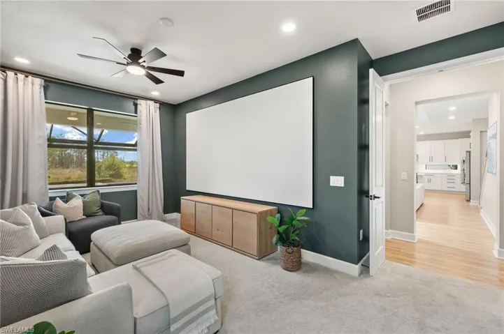 Home theater featuring light carpet, baseboards, ceiling fan, and visible vents
