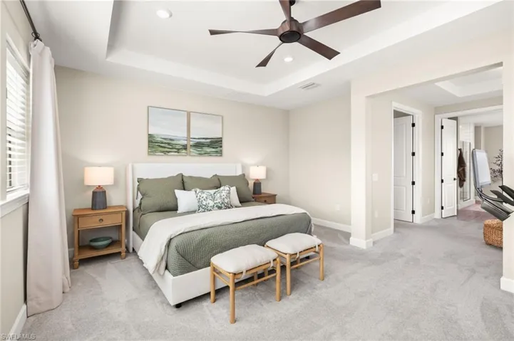 Bedroom with a tray ceiling, recessed lighting, baseboards, visible vents, and light carpet