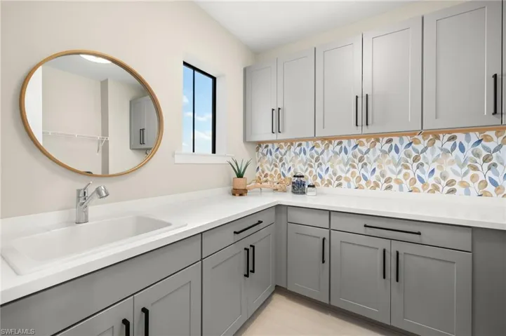 Kitchen featuring gray cabinetry, light countertops, a sink, and tasteful backsplash