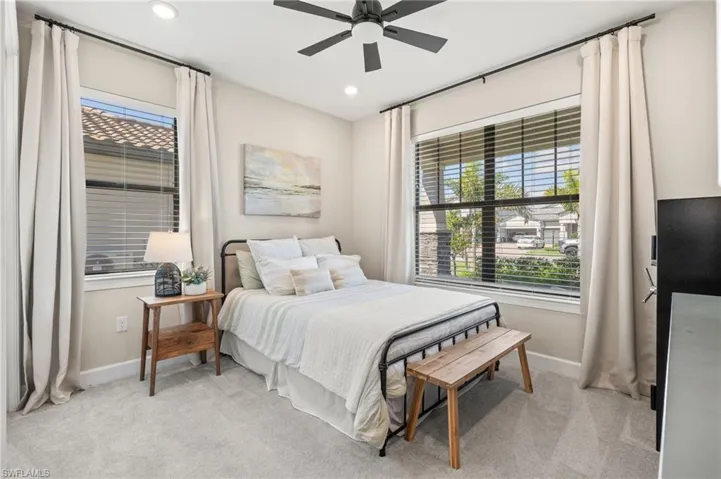 Bedroom with baseboards, multiple windows, and light carpet