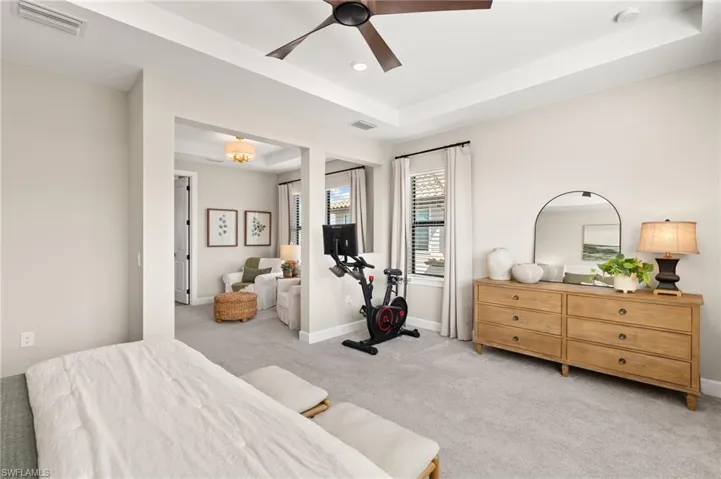Bedroom with a raised ceiling, light carpet, baseboards, and visible vents