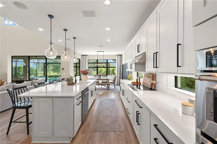 Kitchen featuring visible vents, a kitchen bar, stainless steel appliances, under cabinet range hood, and a sink
