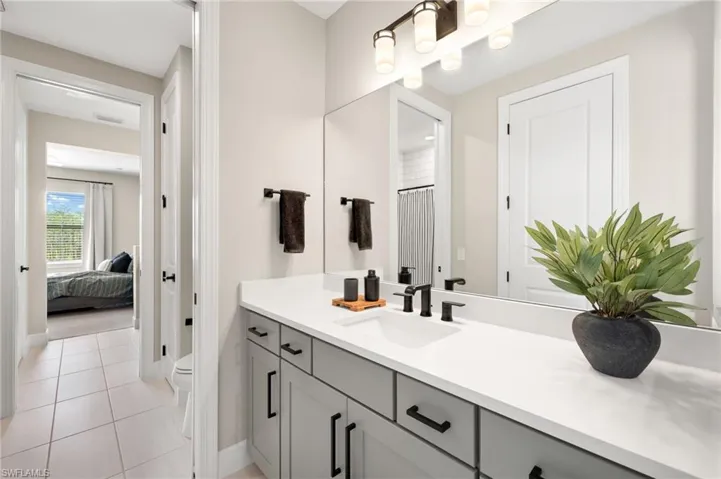 Bathroom featuring visible vents, connected bathroom, toilet, vanity, and tile patterned flooring