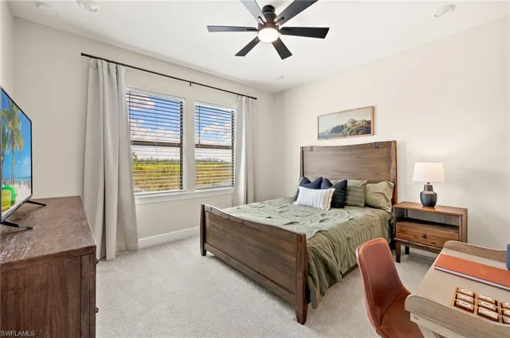 Bedroom featuring light carpet, baseboards, and ceiling fan