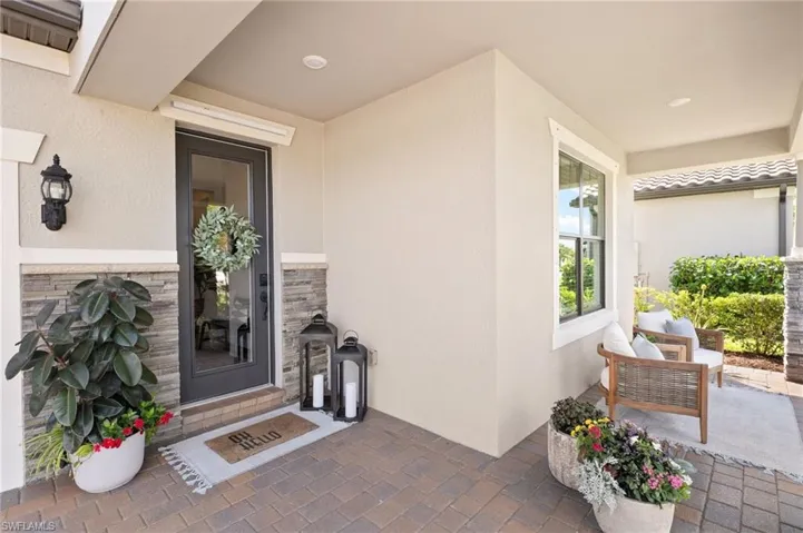 View of exterior entry featuring visible vents, stucco siding, and stone siding