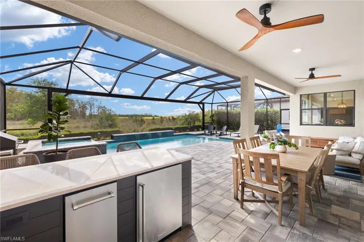 View of patio / terrace featuring a jacuzzi, outdoor dining area, ceiling fan, and an outdoor pool