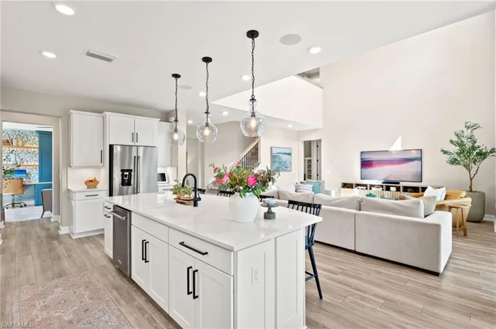 Kitchen featuring white cabinetry, a sink, light wood finished floors, visible vents, and high quality fridge