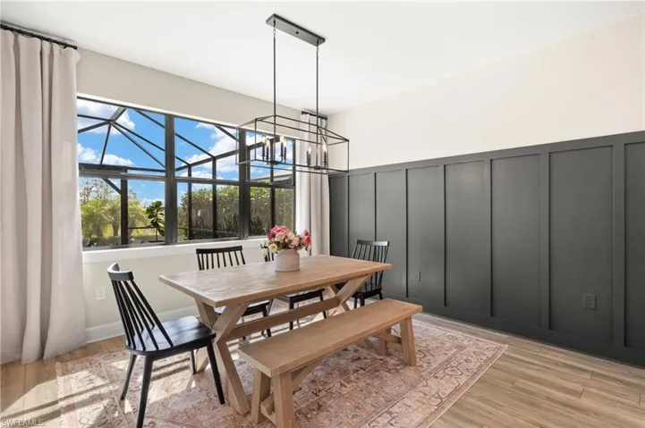 Dining room with light wood-type flooring, a decorative wall, and an inviting chandelier