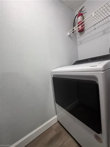 Laundry room with washer / clothes dryer, wood finished floors, and a textured wall