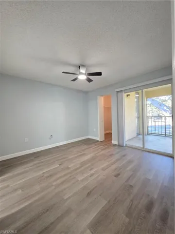 Unfurnished bedroom featuring a spacious closet, a textured ceiling, light wood-style flooring, access to outside, and a ceiling fan