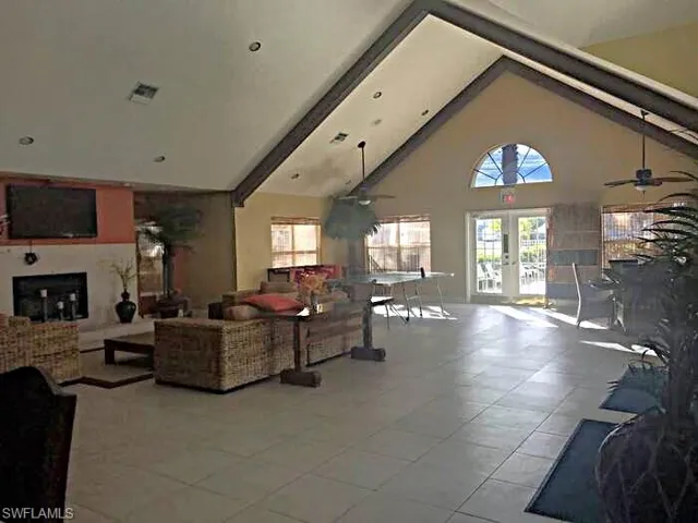 Living room featuring ceiling fan, a fireplace, french doors, and light tile patterned flooring